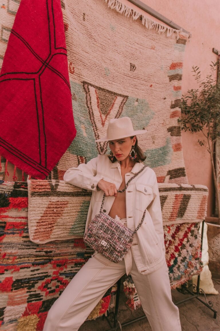 Model in a White Jacket and Pants with a Handbag by the Carpets
